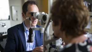 Photograph of Professor Keith Martin examining a patient with an eye scanner.