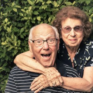 Irene with arms around husband George in their garden