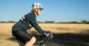 Photo of Jenny Hassell riding her bike with the countryside in the background.