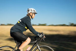 Photo of Jenny Hassell riding her bike with the countryside in the background.