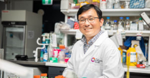 Photo of Associate Professor Rick Liu sitting at a lab bench surrounded by equipment.