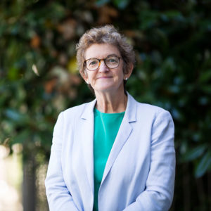 Head and shoulders photograph of Professor Robyn Guymer AM standing face to camera, smiling.