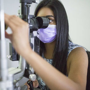 A head and shoulders shot of a researcher examining a patient's eye.