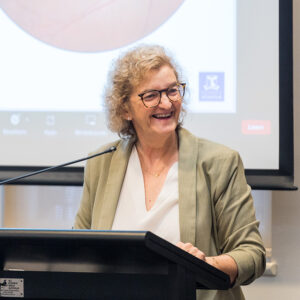 Professor Robyn Guymer standing in front of a lectern, giving a presentation.