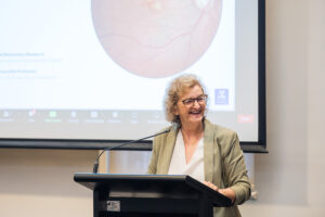 Professor Robyn Guymer standing in front of a lectern, giving a presentation.