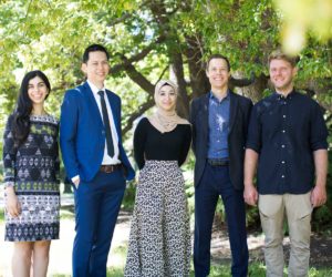 Group photograph of five CERA researchers and staff members standing outdoors in a park, with trees in the background, standing face to camera, smiling.