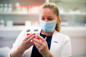 Heather Machin holding several sample jars filled with a red liquid