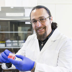 Head and shoulders image of Dr Karl Brown holding tissue sample.