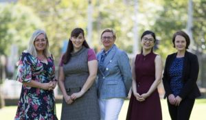 A group of researchers standing in a row smiling. they are outdoors on a sunny day. They are, from left, Nicole Tindill, Dr Myra McGuinness, Associate Professor Heather Mack, Dr Cee Cee Britten-Jones and Associate Professor Lauren Ayton.