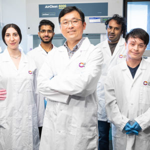 Rick Liu surrounded by four members of his team in the lab