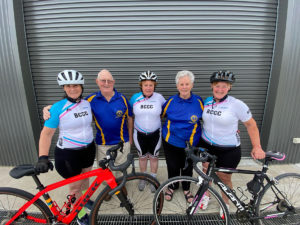 Three sisters in cycling gear, standing with their parents in front of two road bikes.