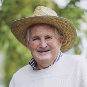 Head and shoulders image of clinical trials volunteer Peter Pittman who is standing in a park, smiling, wearing a hat and looking directly at the camera.