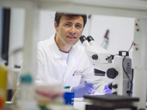 Dr Luis Alarcon-Martinez leaning over a microscope in his lab