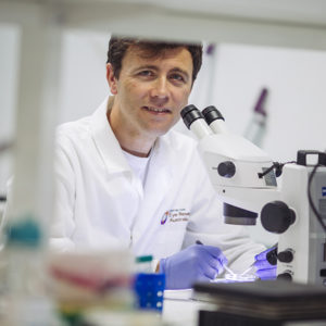 Dr Luis Alarcon-Martinez leaning over a microscope in his lab