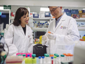 Dr Jennifer Fan Gaskin and Associate Professor Guei-Sheung (Rick) Liu are standing side by side in lab coats looking at a sample.