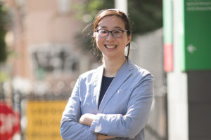 Dr Sandy Hung, standing outside a building and smiling while facing the camera.