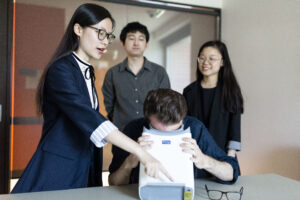 Image of Lisa Zhou pointing to an eye scanner.