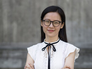 Head and shoulders shot of Dr Lisa Zhuoting Zhu who is crossing her arms and smiling direct to camera.