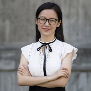 Head and shoulders shot of Dr Lisa Zhuoting Zhu who is crossing her arms and smiling direct to camera.